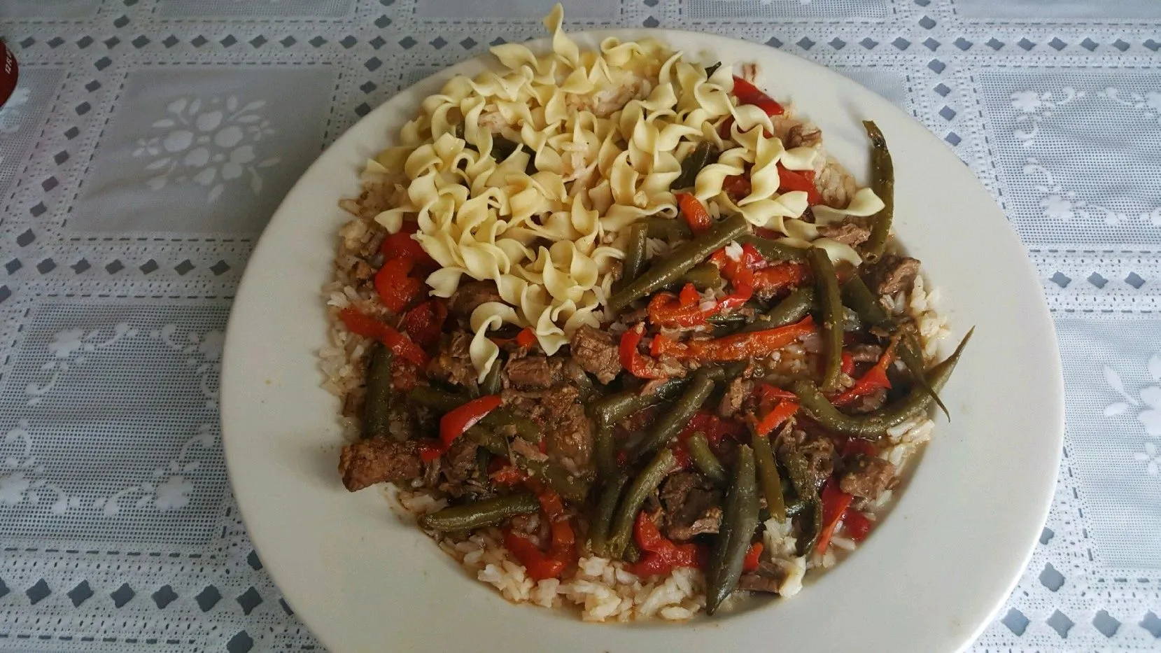 Beef goulash with green beans, sweet peppers, and egg noodles over rice