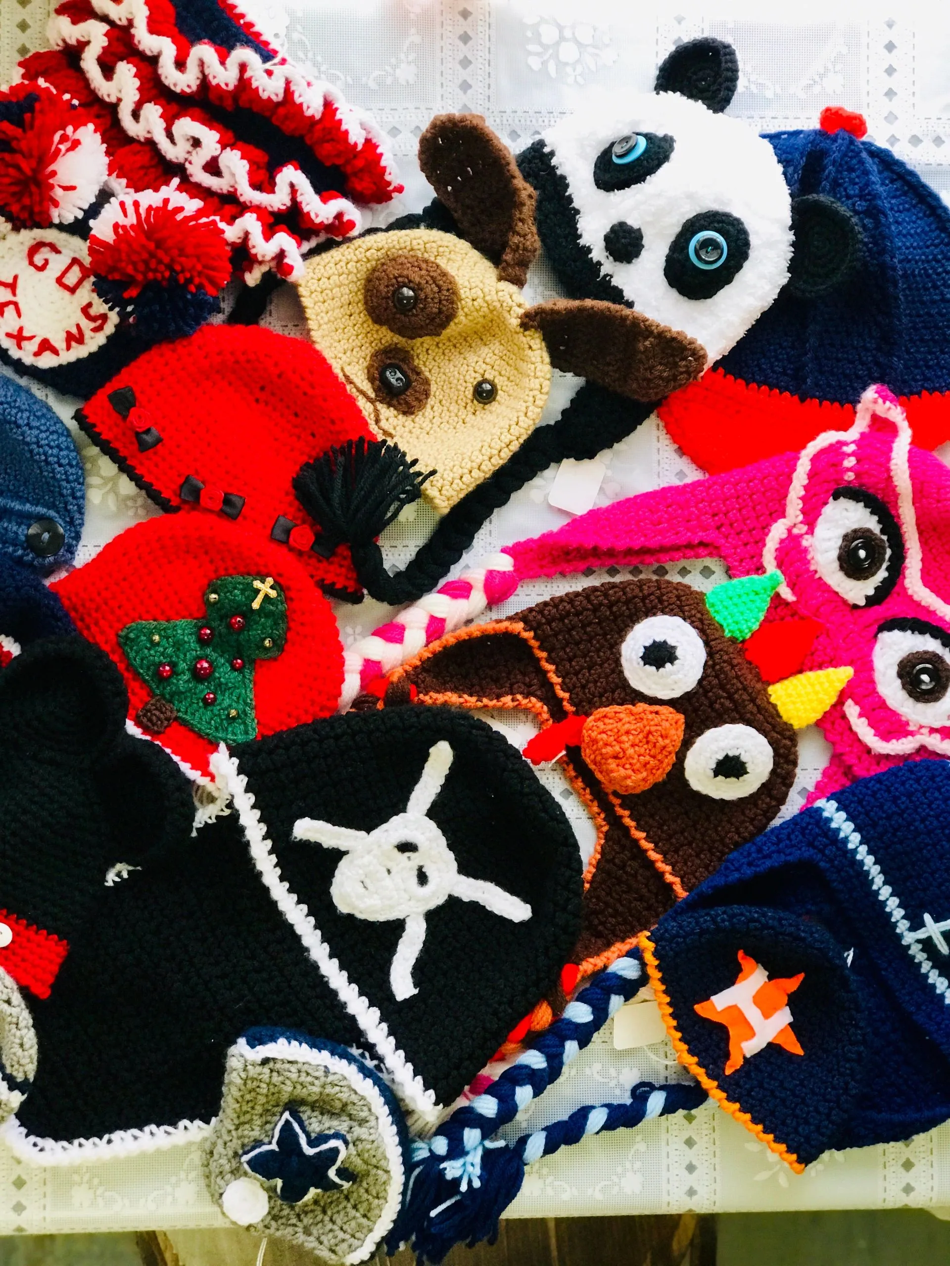 Mila's handmade crocheted hats — panda, dog, owl, Houston Texans, Astros, and more