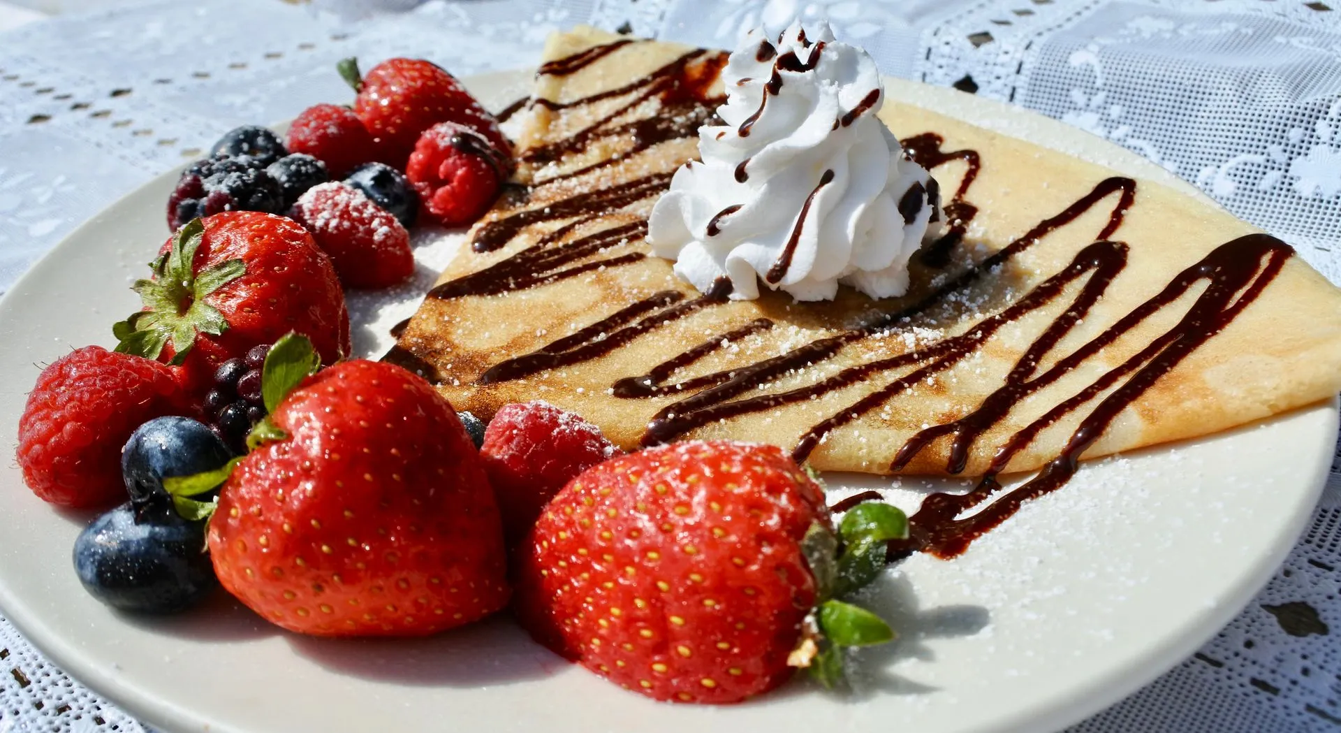 Sweet Siberian crepe with fresh berries, chocolate sauce, and homemade whipped cream